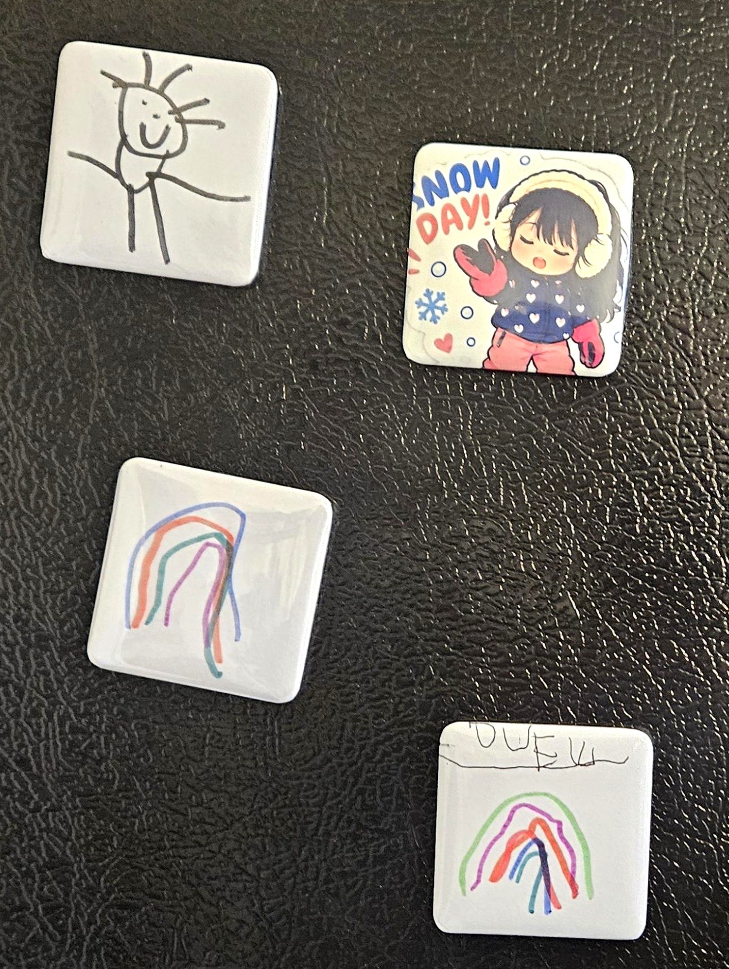 Kids drawings turned into magnets on a fridge